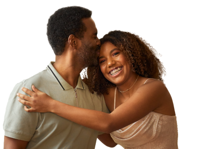 A father kissing his daughter on the forehead as she wraps her arms around him and smiles
