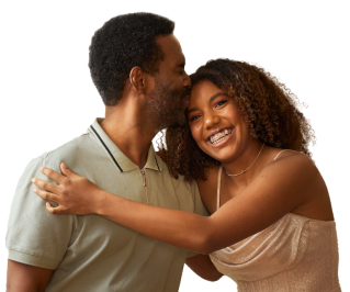 A father kissing his daughter on the forehead as she wraps her arms around him and smiles